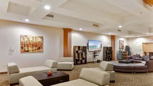 A spacious lobby with multiple seating areas, a large painting, and a television. - Bluebird Suites at the Warehouse District (Cleveland)