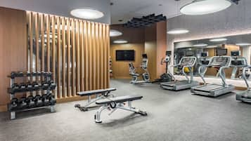 Ein modernes Fitnessstudio mit Laufbändern, Crosstrainern und Kurzhanteln.