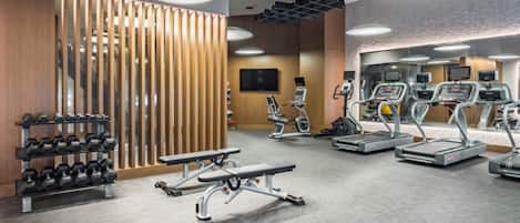 Un gimnasio moderno con cintas de correr, elípticas y pesas libres.