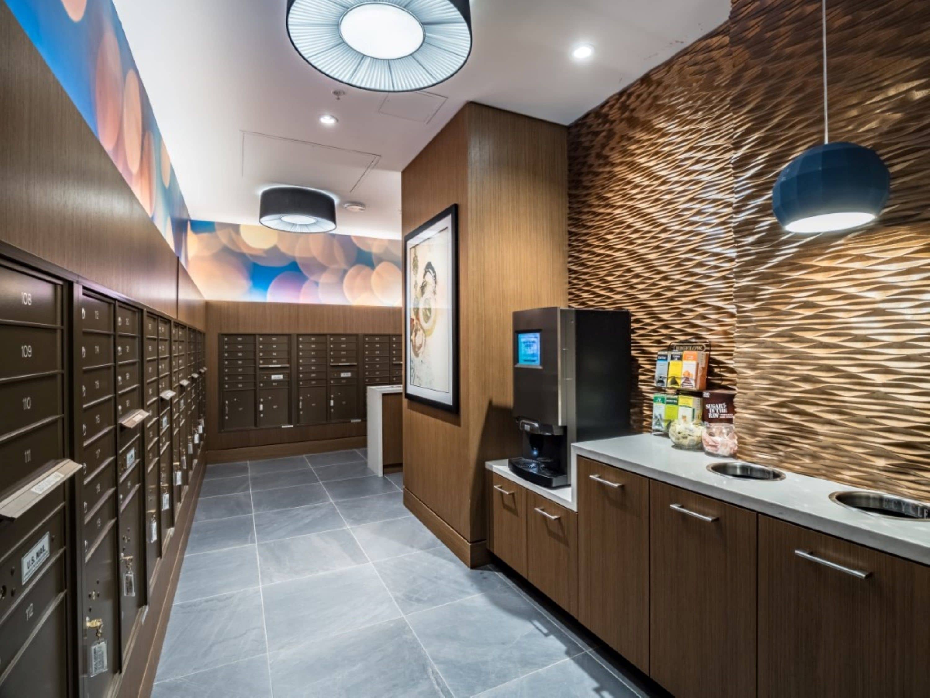 Rebedor modern d'hotel amb una màquina de cafè, taulers i una paret amb dibuixos.
