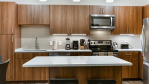 Una cocina moderna con armarios de madera, una isla central, electrodomésticos de acero inoxidable e iluminación bajo los armarios.