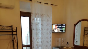 Une chambre d’hôtel comprenant un lit, une commode, une télévision et une salle de bain avec un rideau de douche.