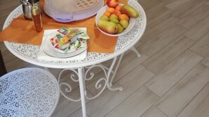 Une cuisine avec des meubles en bois, un four à micro-ondes, un évier et une table sur laquelle se trouvent un panier de fruits et des condiments.