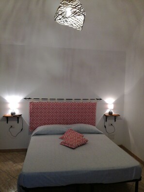 Une chambre à coucher avec un lit, une tête de lit à motifs, des lampes de chevet et un luminaire suspendu.