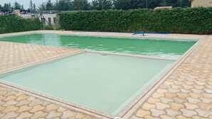 A swimming pool with a tiled deck and a hedge in the background. - Too's Nest Edoret (Eldoret)