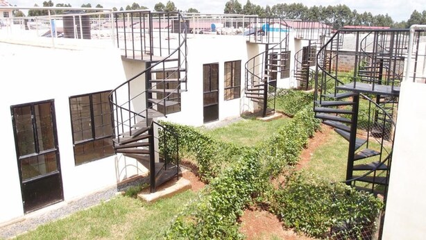 A building with multiple staircases leading to upper floors, surrounded by a garden with green plants. - Too's Nest Edoret (Eldoret)