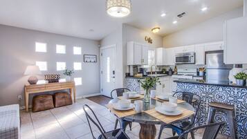 Una cocina moderna con armarios blancos, microondas y una estación de café.