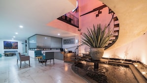 Un vestíbulo amplio con diseño moderno, que incluye una zona de estar, una escalera y una planta grande en maceta.