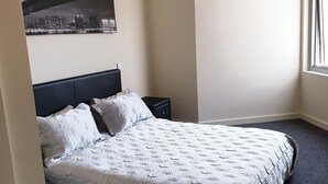 A bedroom with a bed, a nightstand, a wall-mounted picture, and a window. - Modern 2b2b apartmemt. close to water front (Point Frederick)