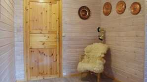 Una habitación con paneles de madera, una puerta de madera, un sillón mullido y tres platos decorativos en la pared.