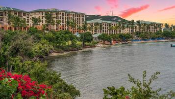A hotel with multiple floors, a waterfront view, and lush greenery.