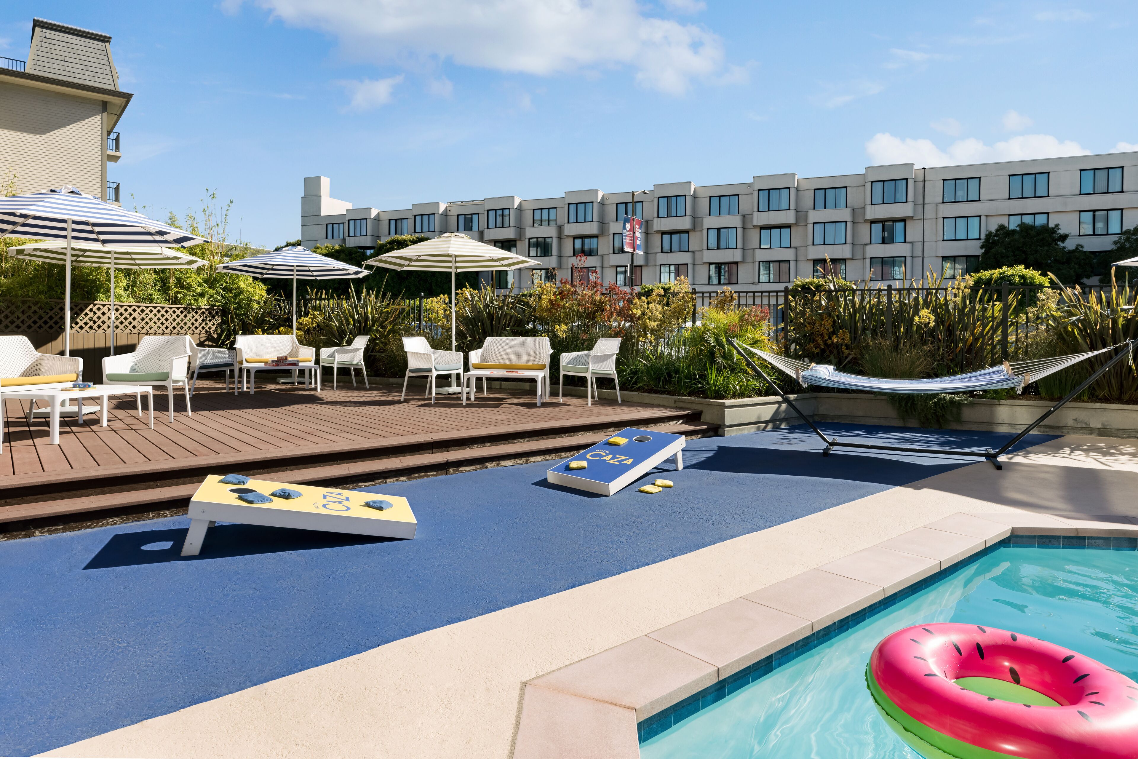 A pool area with lounge chairs, umbrellas, and a hammock.