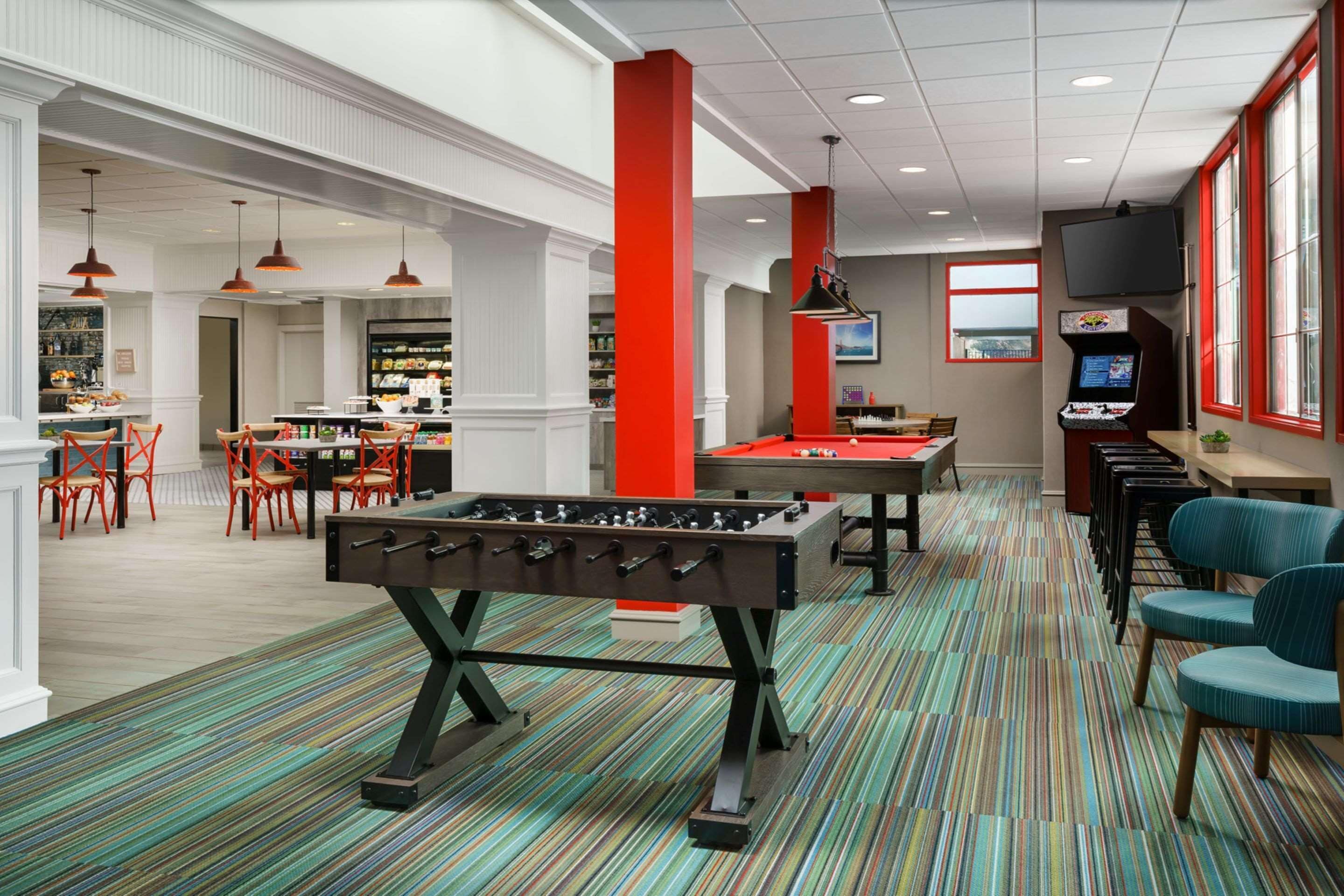 A spacious lobby with a foosball table, seating area, and a bar.