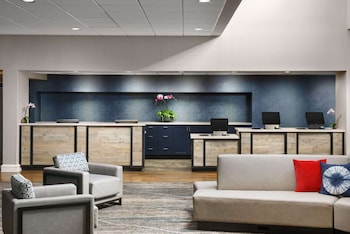 A spacious lounge area with seating, a bar, and large windows offering views of the street. at Hotel Caza Fisherman´s Wharf