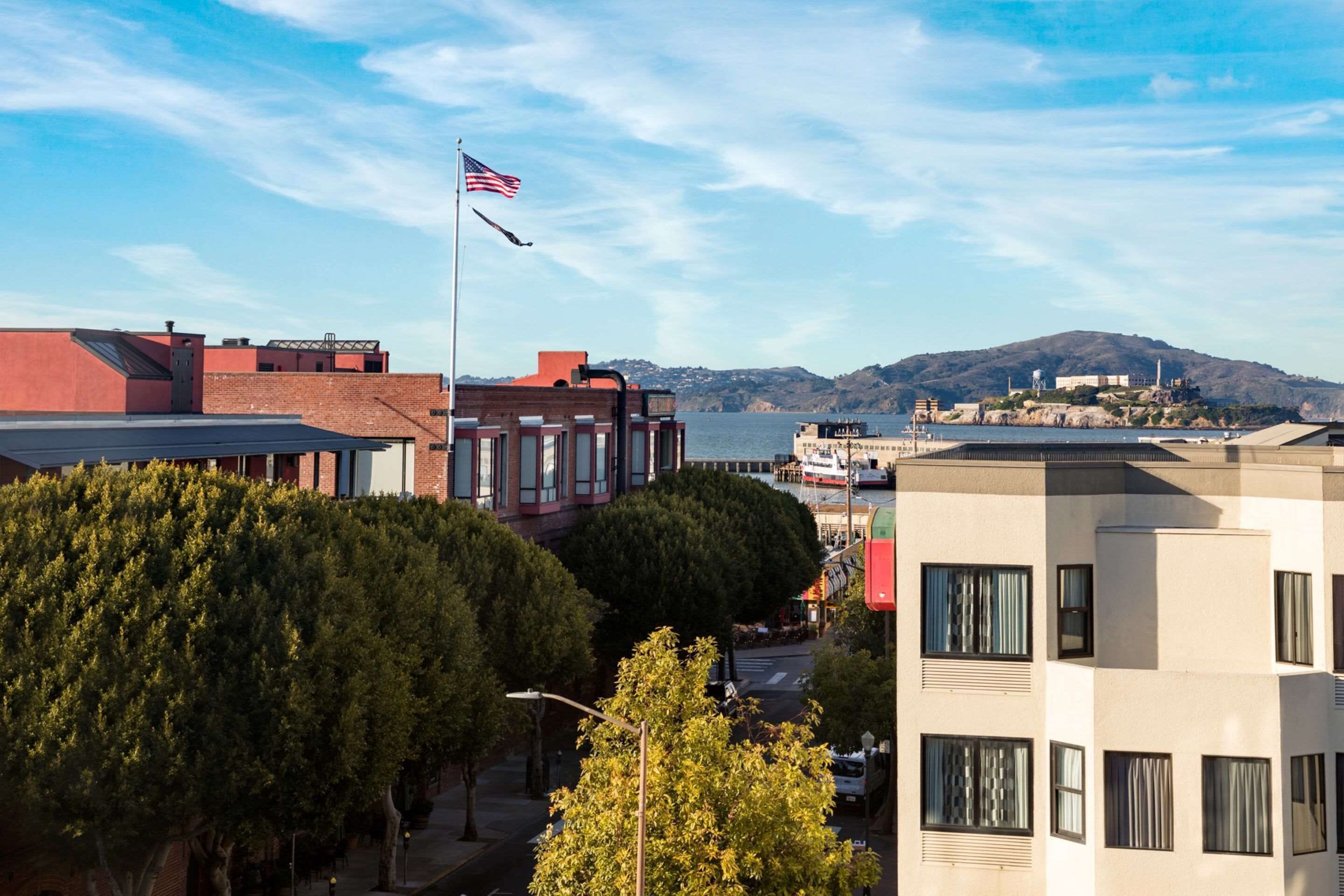 A cityscape with modern buildings, a flag, and a distant hill.
