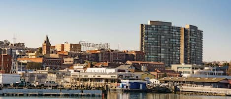 A waterfront cityscape with a prominent high-rise building, a historic church, and a marina with boats.