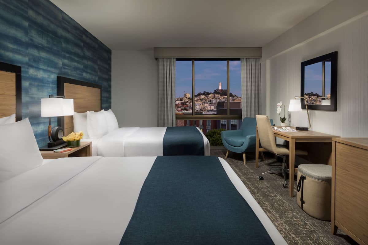 Una camera d'albergo con un letto grande, una scrivania, una sedia e vista sulla città.
