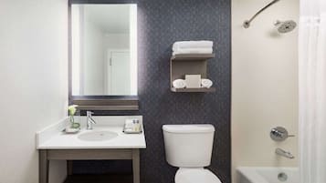 A modern bathroom with a white sink, mirror, and toilet. There is a towel rack above the toilet and a shower curtain visible.