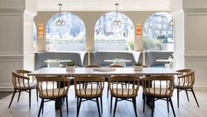 A dining area with a long table, six wooden chairs, and two sofas.
