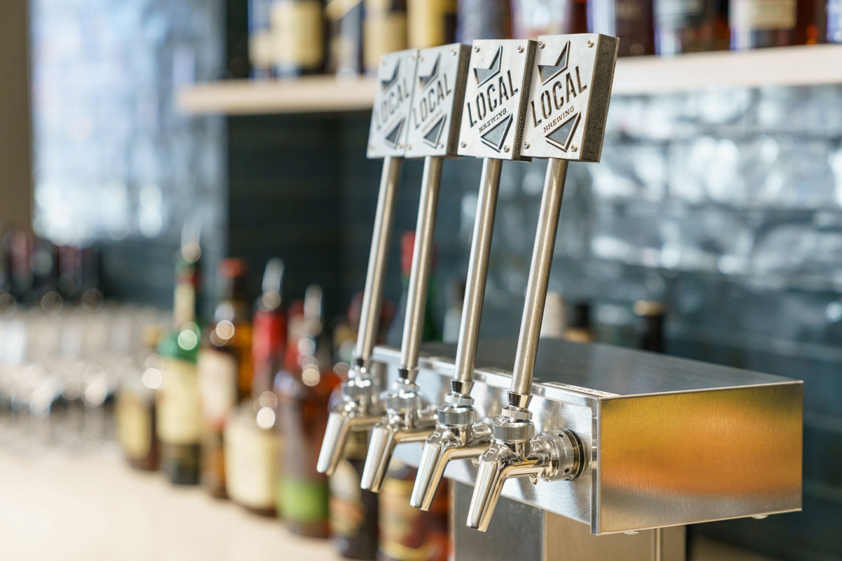 A row of beer taps labeled "Local Brewing" in a bar setting.