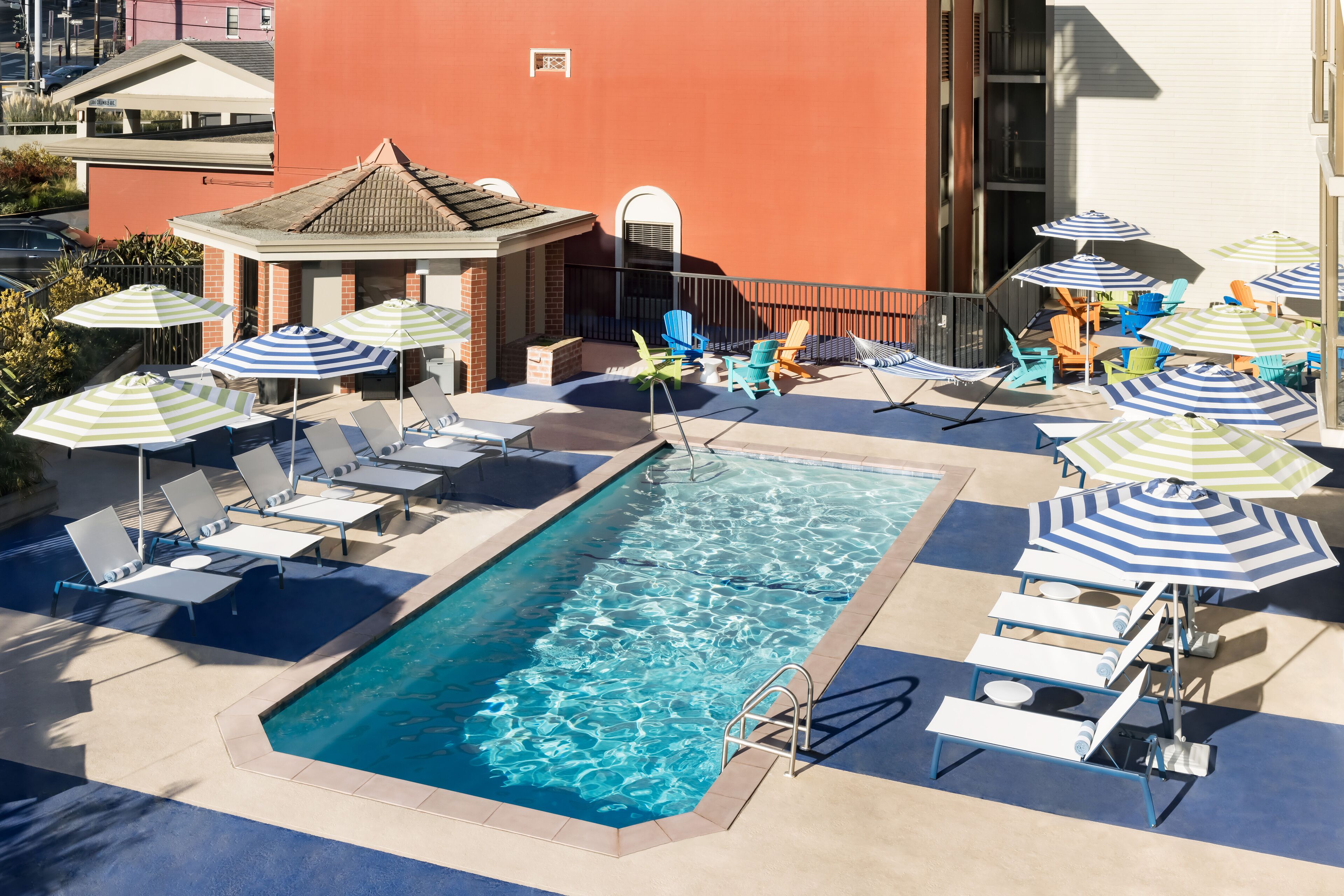 Un área de piscina en la azotea con sillones y sombrillas.