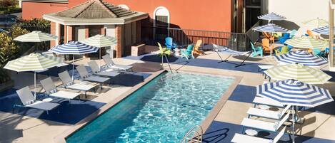A rooftop pool area with lounge chairs and umbrellas.