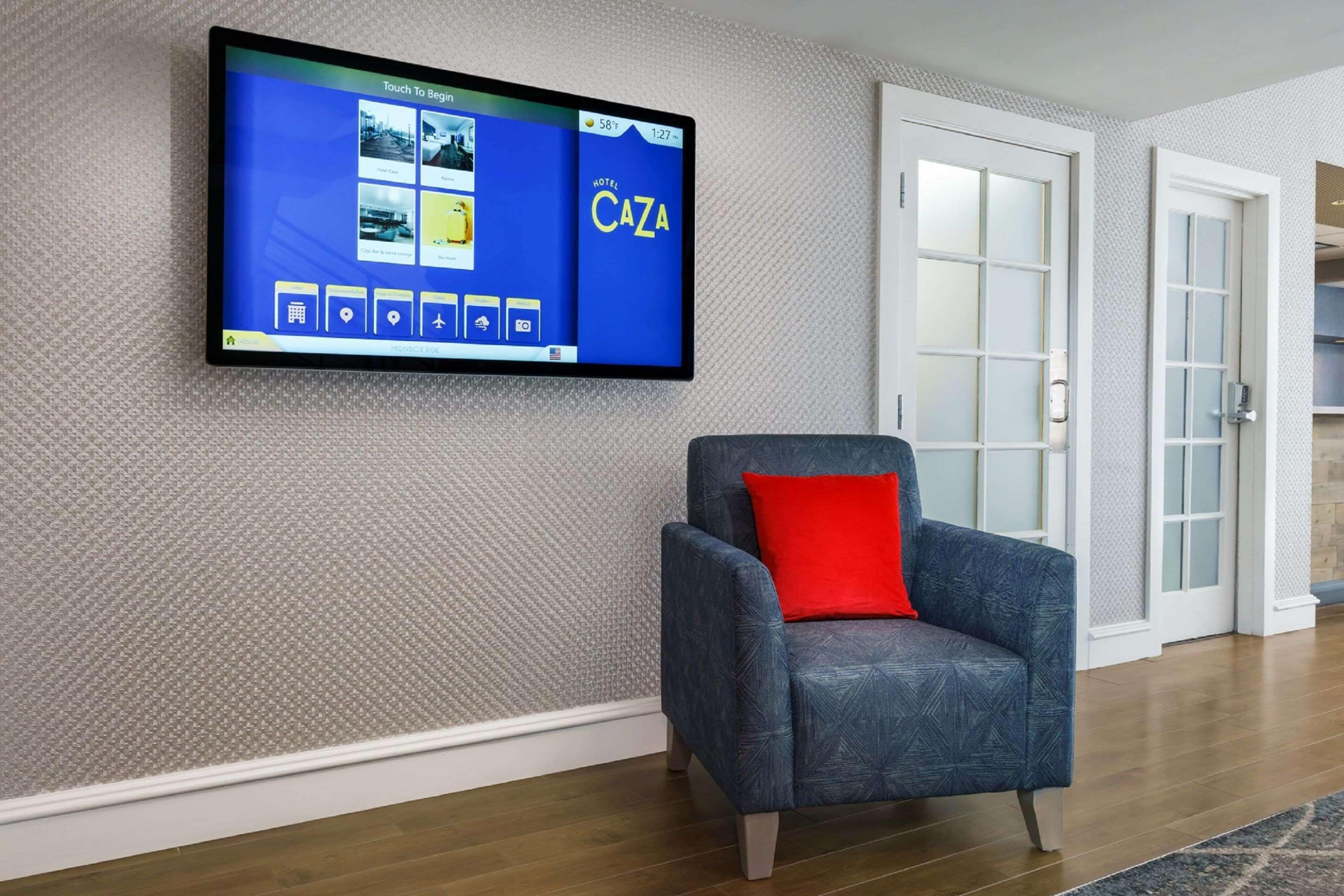 Et hotelværelse med et stort fladskærms-tv på væggen, der viser et hotelinterface.