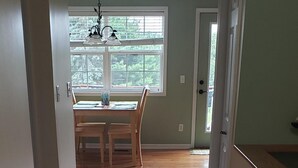 A hallway with wooden flooring leading to a dining area with a table and chairs. - Come and enjoy beautiful Torch Lake! (Bellaire)