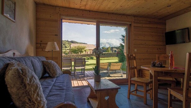 Una cabaña de madera acogedora con sofá, una mesa y televisión.