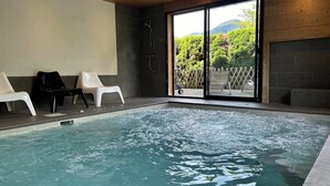 Una piscina con agua cristalina, rodeada de sillas blancas y vistas a zonas verdes.