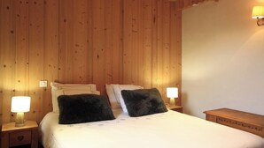 Una habitación con paneles de madera, una cama, dos mesitas de noche y una lámpara de pared.