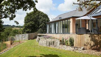 A modern house with large windows, a stone retaining wall, and a well-maintained lawn.