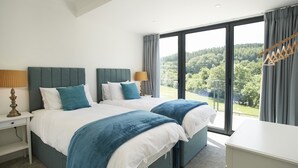 A hotel room with two beds, a large window with a view of a forest, a bedside table with a lamp, and a wardrobe. - Set in the tranquil Teign Valley, Teign Vale makes the most of its position (Drewsteitgnton)