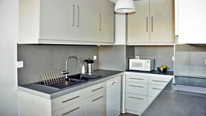 A modern kitchen with white cabinets, a stainless steel sink, and a microwave. - In Paris, for 1 month or more! (Paris)