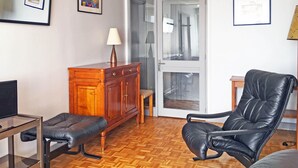 A living room with a wooden cabinet, a black leather chair, a small table, and a television. - In Paris, for 1 month or more! (Paris)