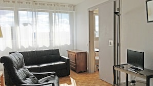 A living room with a sofa, a chair, a TV on a stand, and a wooden floor. - In Paris, for 1 month or more! (Paris)