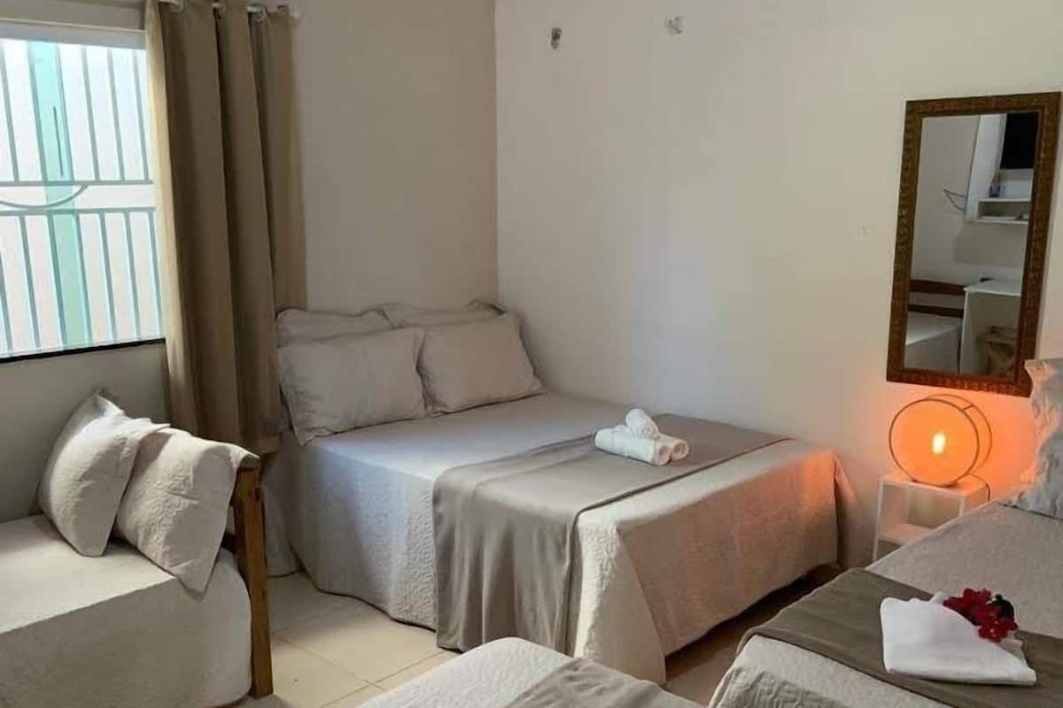Ein Hotelzimmer mit zwei Einzelbetten, einem Sofa, einem Nachttisch mit Lampe und einer Klimaanlage.