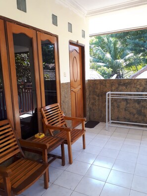 A room with wooden benches and a door, a tiled floor, and a view of greenery outside.