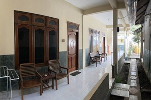 A corridor with wooden benches and doors, a tiled floor, and a small water feature.