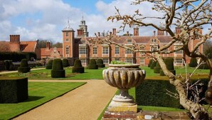 A formal garden with a central pathway leading to a large building with a tower. - Fo'c'sle, Wiveton, Norfolk (Wiveton)