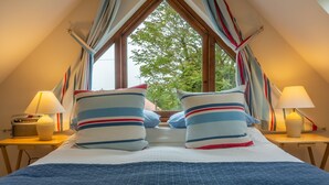 A bedroom with a large window, striped pillows, and bedside lamps. - Fo'c'sle, Wiveton, Norfolk (Wiveton)