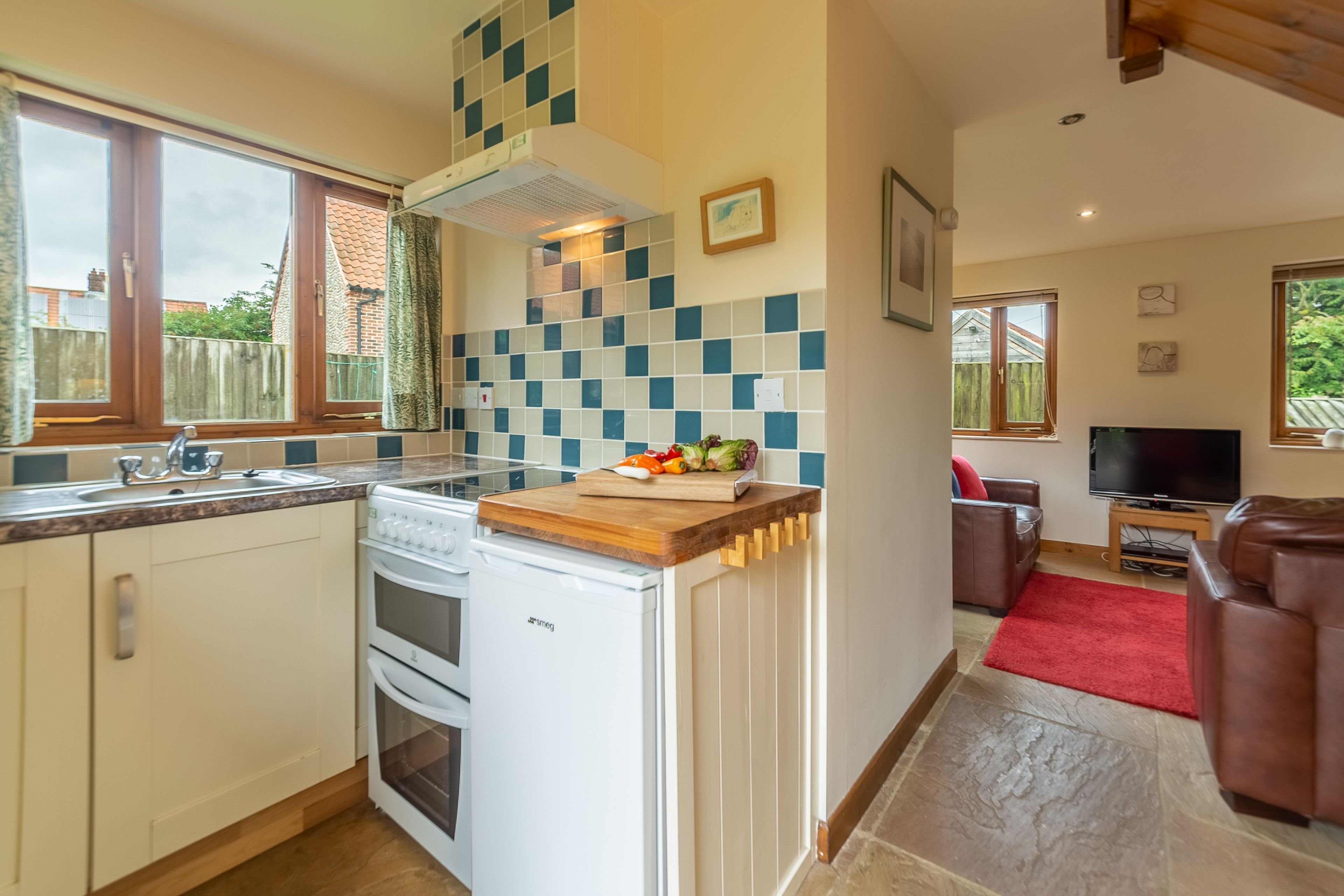 A compact kitchen with a built-in oven, a white dishwasher, and a wooden countertop.