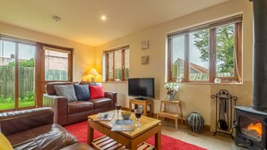 A cozy living room with a fireplace, leather sofas, a TV, and a red carpet. - Fo'c'sle, Wiveton, Norfolk (Wiveton)