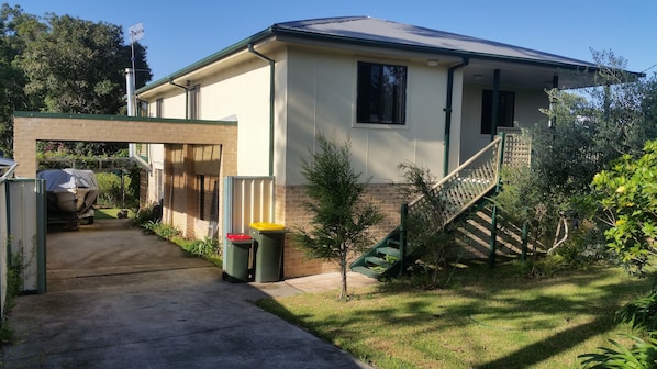 A single-story house with a covered driveway, a small front yard, and a staircase leading to the entrance.
