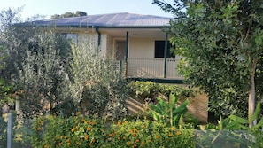 A house with a balcony, surrounded by various plants and flowers.