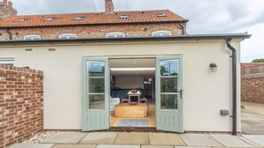 Une maison moderne dotée d’une véranda avec un banc en bois et une petite table.