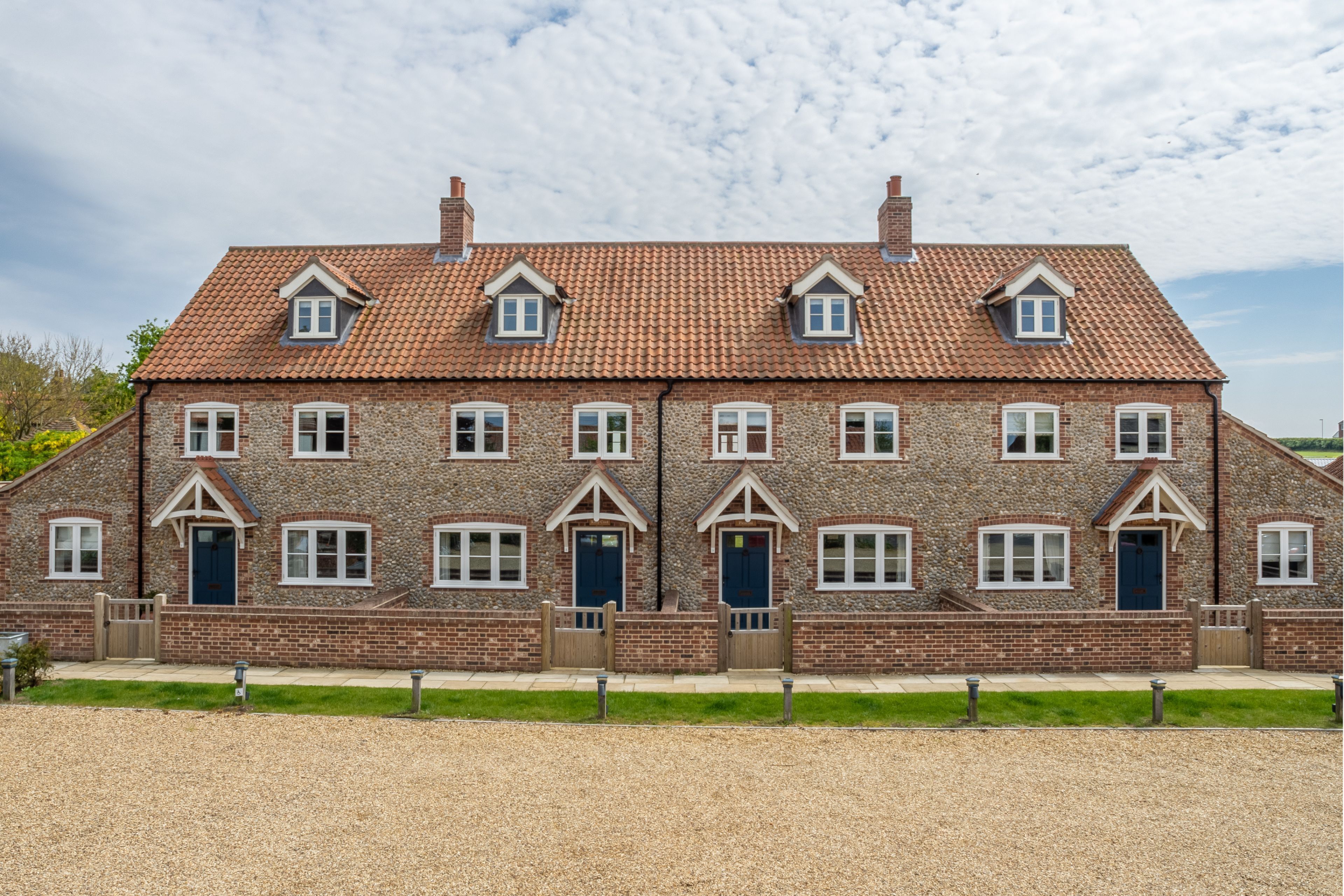 A two-story brick house with a tiled roof, multiple windows, and a front door.