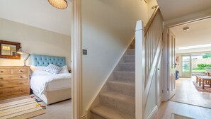 Une chambre à coucher comprenant un lit, une commode, un miroir et un escalier menant à une autre pièce.