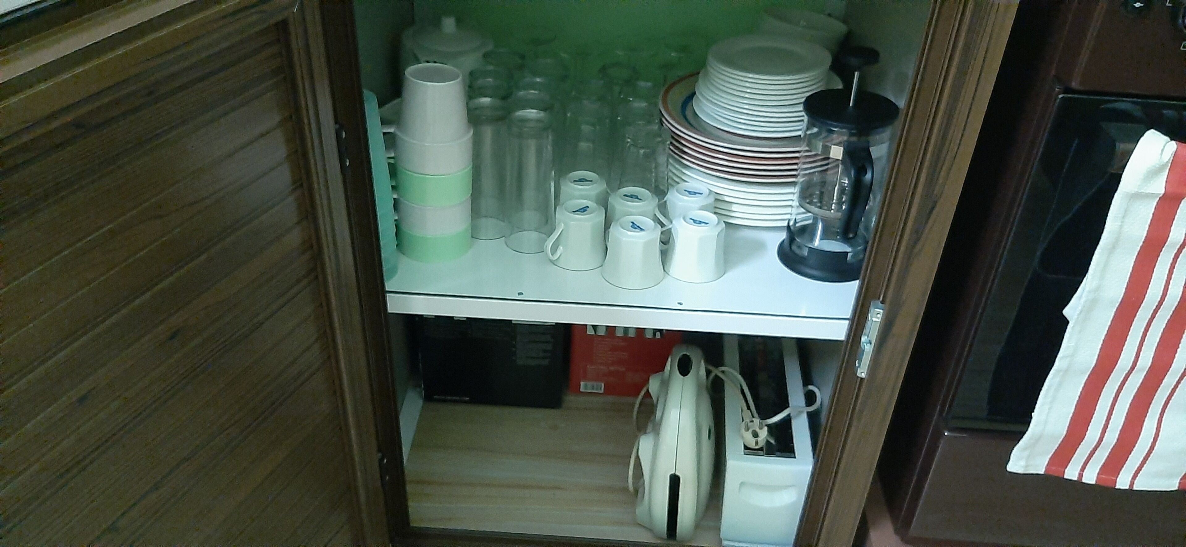 Una cocina con un armario de madera, una encimera con diversos utensilios y una caja roja.