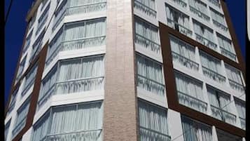 Un edificio alto y moderno con varios pisos, que presenta una columna vertical central y numerosas ventanas.